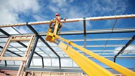 Man in an elevated working platform inspecting building framing